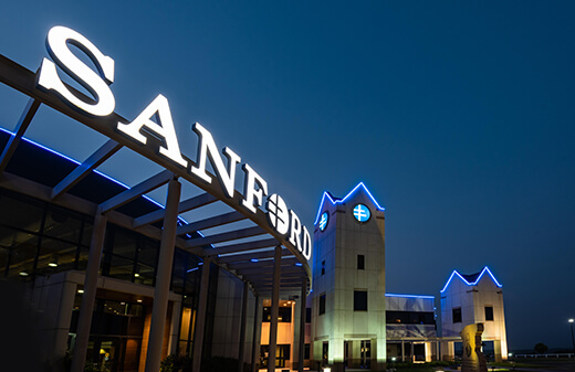 Partnering with Sanford Health Sanford Center exterior sign at night.