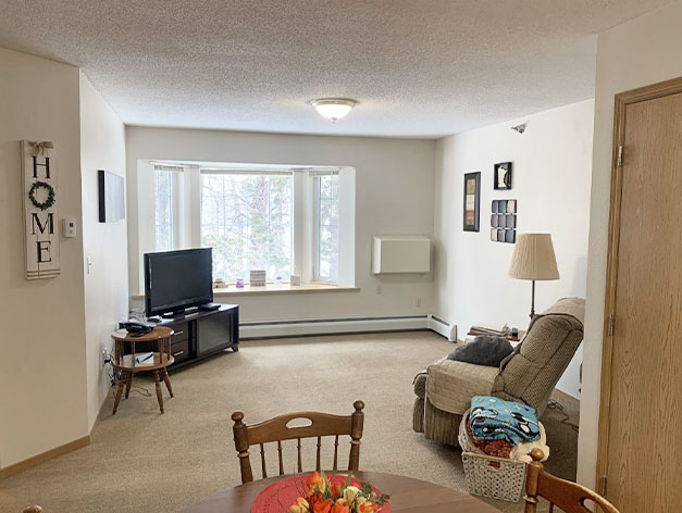 Senior living apartments feature spacious living rooms with natural light at Good Samaritan Society - Hidewood Estates in Clear Lake, South Dakota.