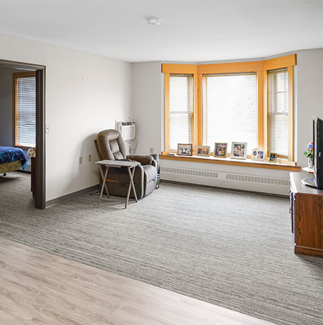 Large open living room with bedroom for senior living residents living in the Maples at Good Samaritan Society - Heritage Grove in East Grand Forks, Minnesota.