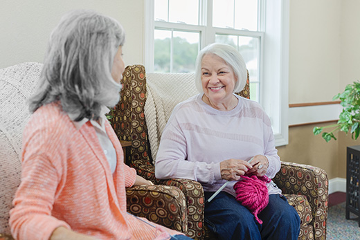 2 ladies knitting in chairs.