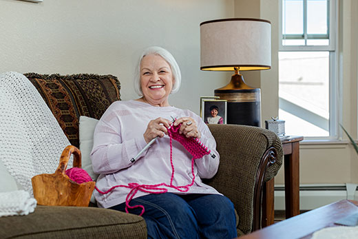 Woman smiling while knitting.