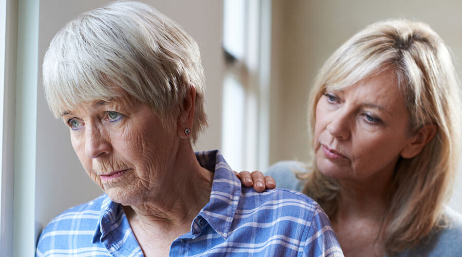 Sad woman with a woman behind comforting her.