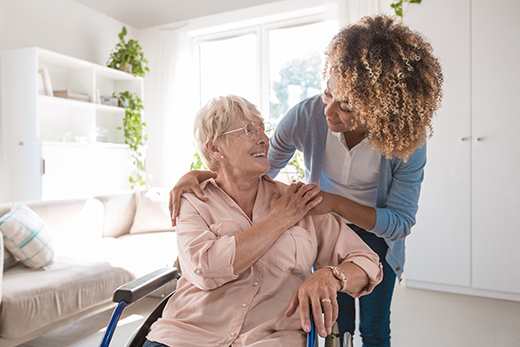 Woman exchanging smiles with a senior in a wheelchair.