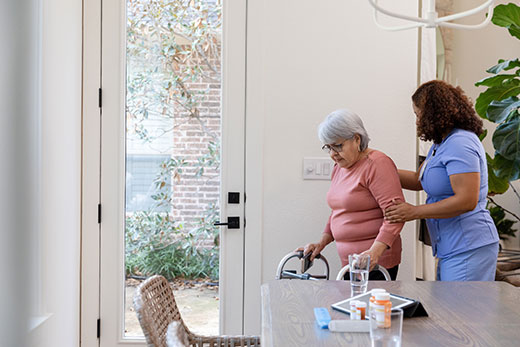 Nurse helping a woman walk with her walker.