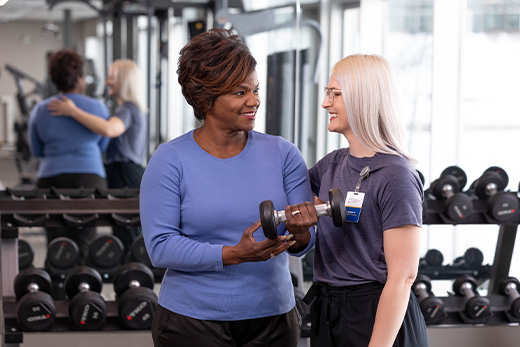 Middle-aged African American woman lifting a weight with assistance of a physical therapist at Good Samaritan Society.
