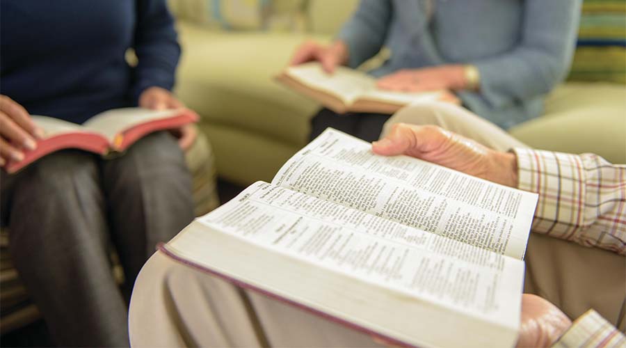 Three people sitting with bibles on their laps