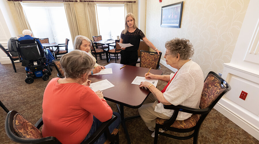 Three female residents and Cedar Lake's wellness director solving a cross puzzle