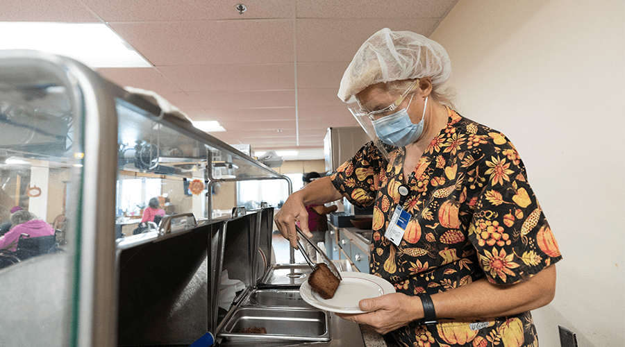 Masked worker dishing up food
