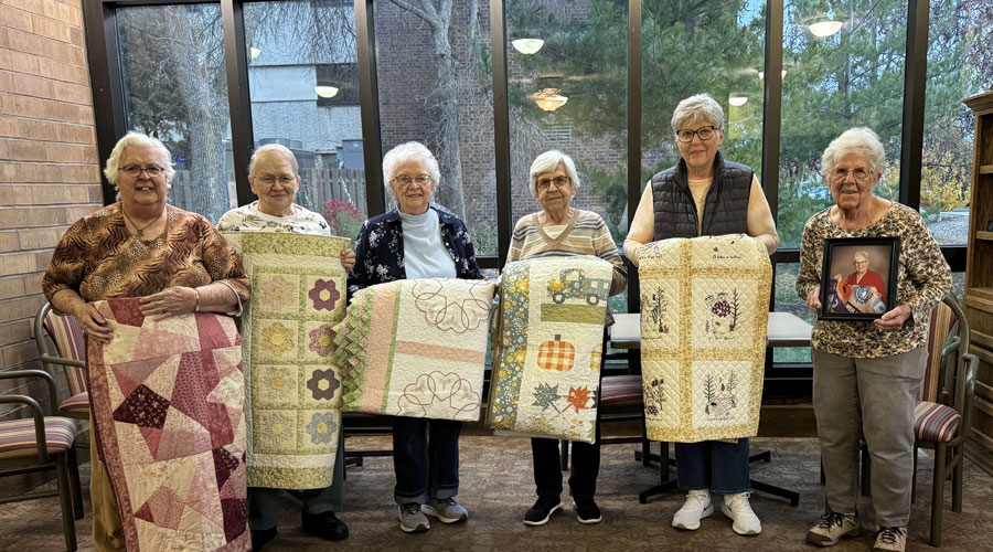 Quilters holding quilts.